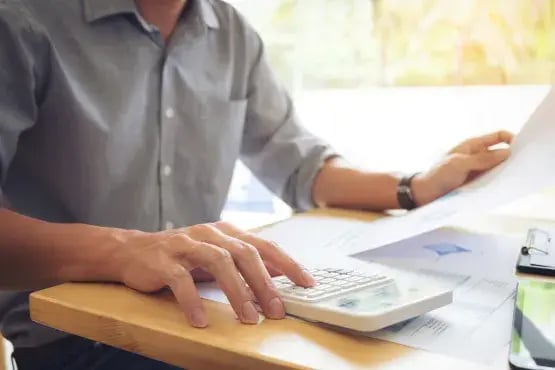 Homme calculant des pénalités de paiement à l’aide de documents financiers