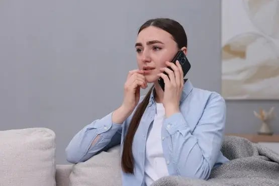 Jeune femme préoccupée parlant au téléphone depuis son canapé