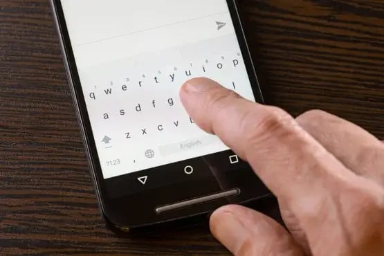 Gros plan sur une main tapant un message de relance sur un smartphone