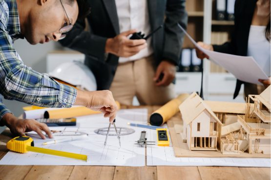 Architectes en réunion autour de plans et d’une maquette de maison