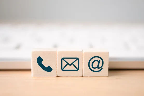 Blocs en bois affichant les icônes téléphone, email et arobase devant un clavier