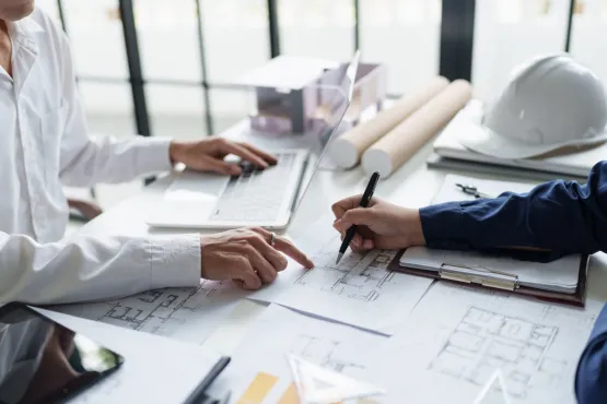 Deux personnes en réunion examinant des plans d’architecture avec un ordinateur