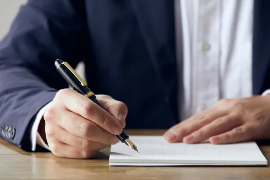 Homme en costume signant un document avec un stylo-plume