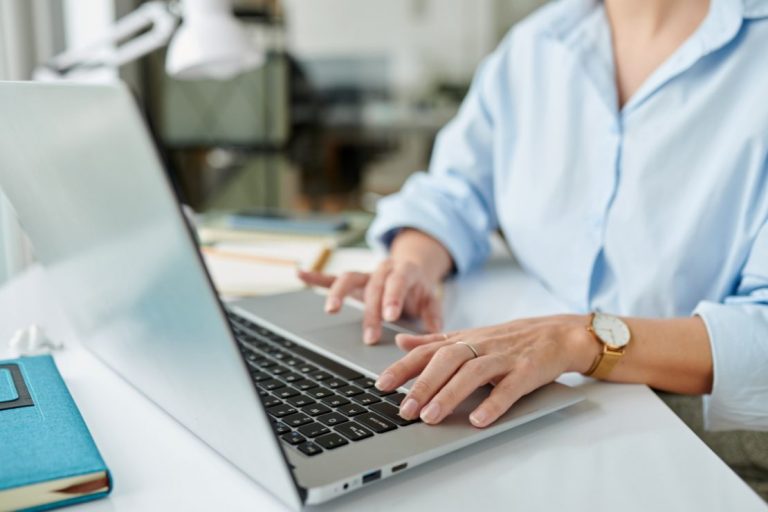 une femme tape sur son clavier pour effectuer un envoi de documents confidentiels par piece jointe sur un ordinateur