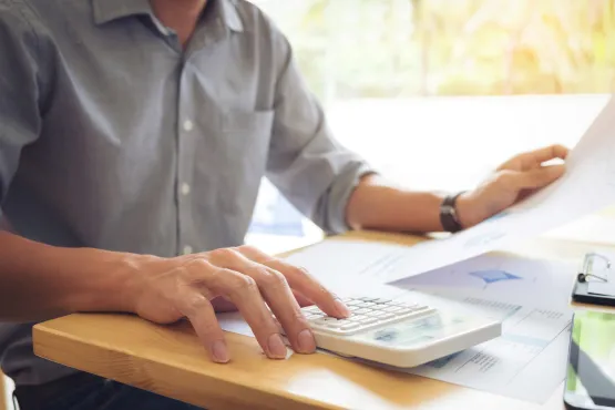 Homme calculant des pénalités de paiement à l’aide de documents financiers